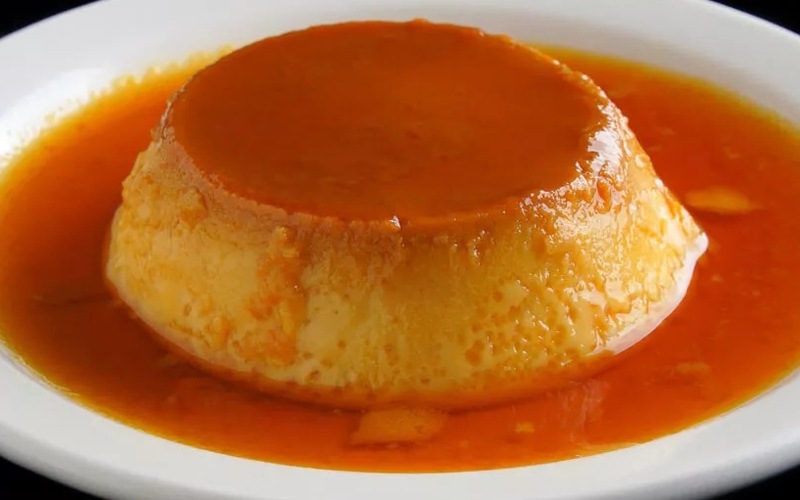 Imagen terminada en plato de crema volteada de quinua en plato, deliciosa preparación a base de huevos, leche condensada y quinua, con caramelo en la parte superior.