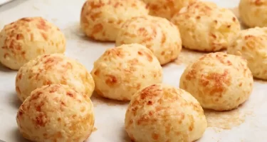 Pan de Yuca y Queso - Deliciosos panecillos dorados de yuca y queso sobre una tabla de madera, perfectos para un snack sin gluten